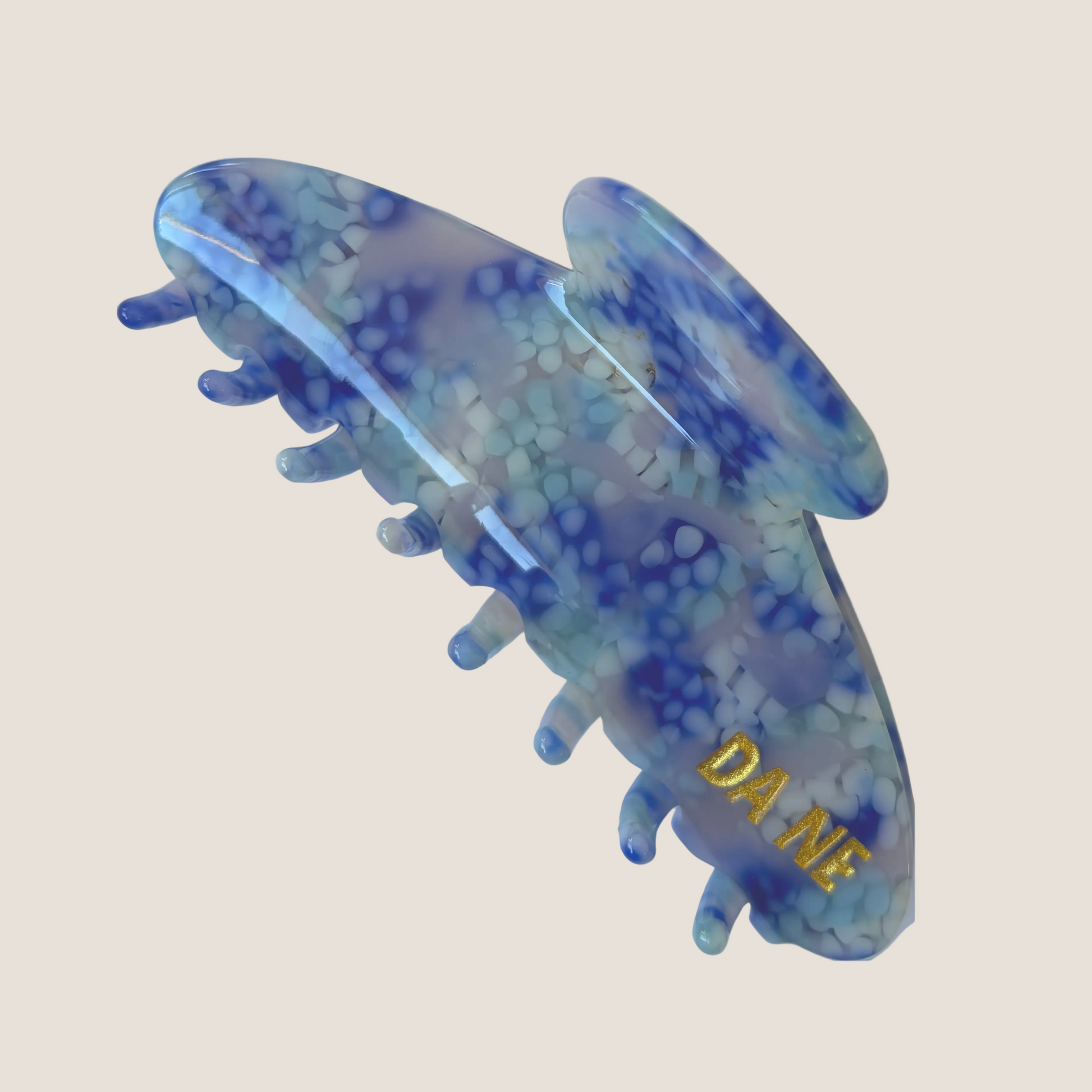 Blue and white patterned hair clip with 'DA NE' branding on a white background
